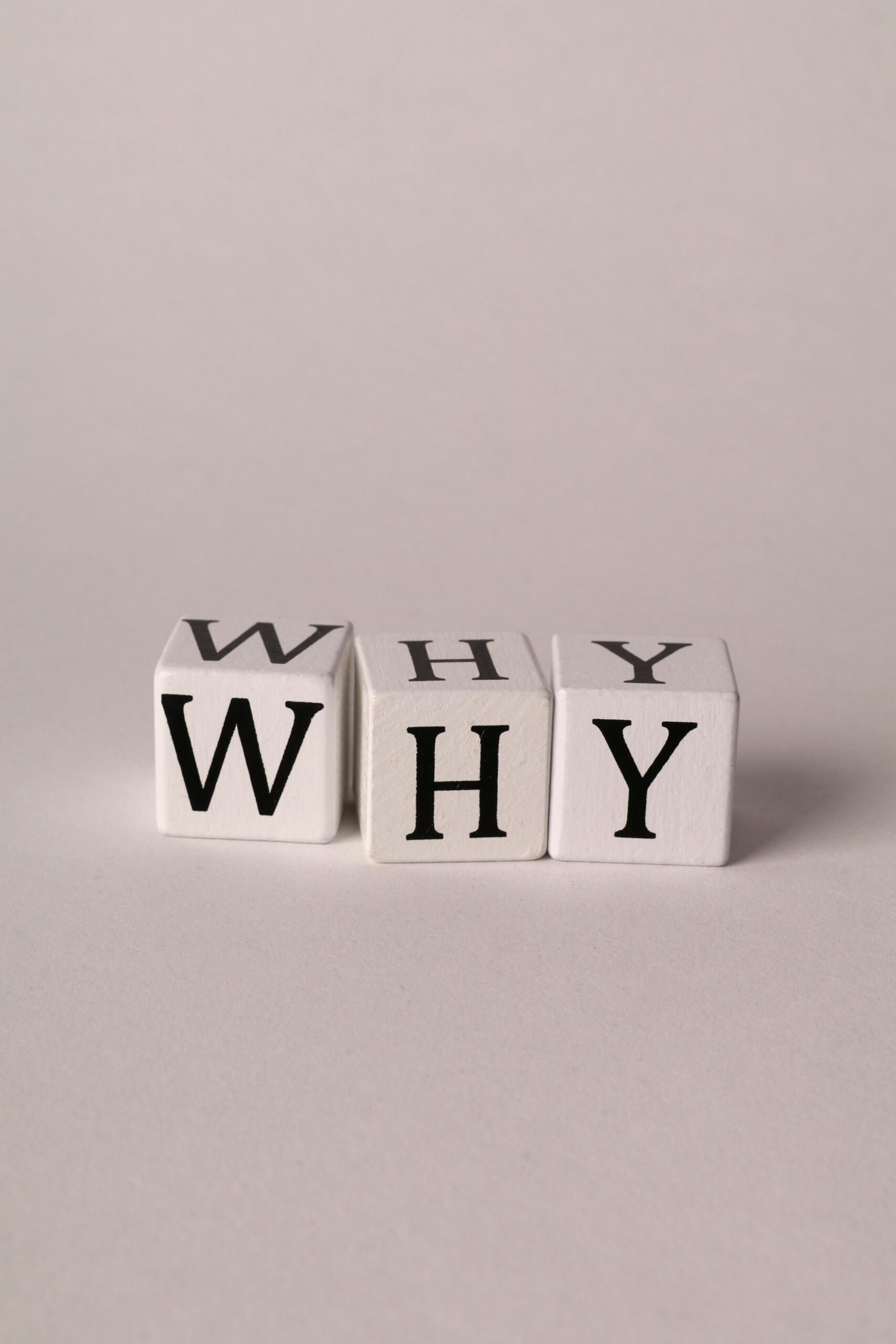 Three cubes spelling 'WHY' on a plain background, symbolizing curiosity and questioning.