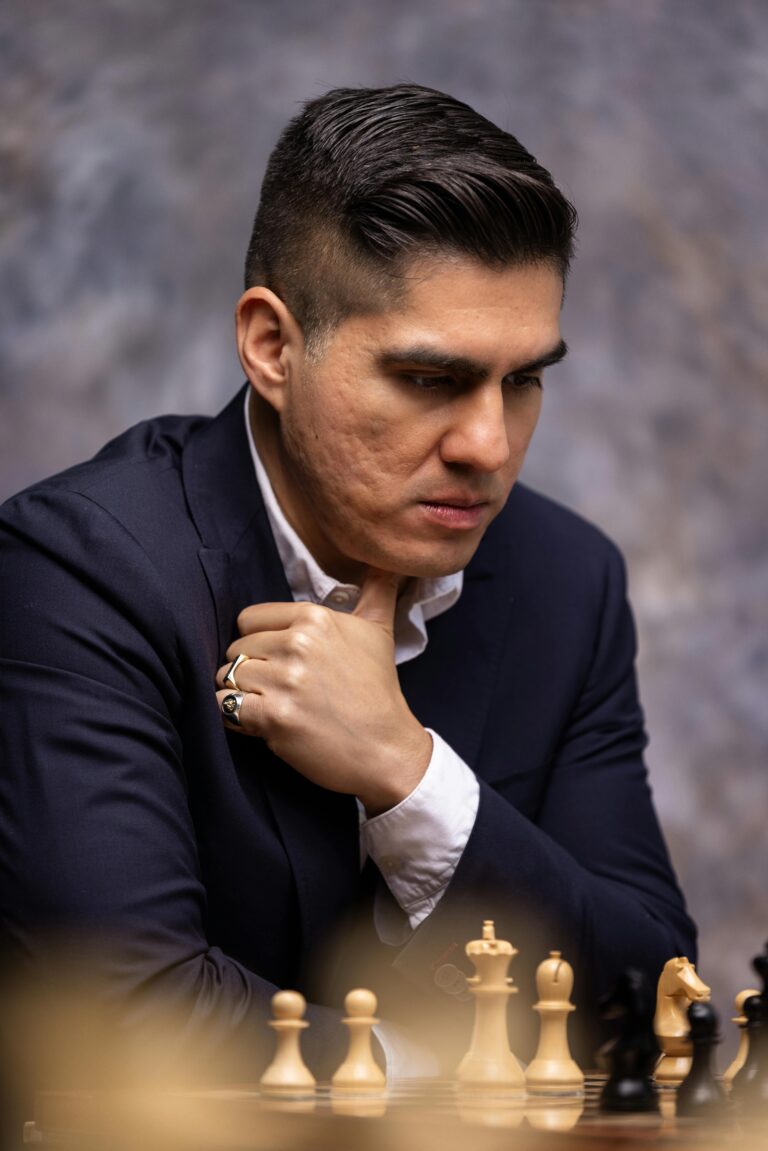 Adult man in a suit deeply focused while contemplating chess moves.